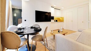 A modern dining area with a round table, chairs, and a flat-screen TV mounted on the wall.