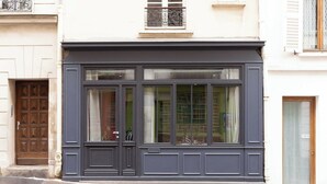 A building facade with large windows, a dark-colored entrance, and a small balcony. - Beautiful Apartment - 1BD/4P - Quartier Latin (Paris)