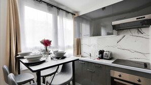 Een moderne keuken met grijze kastjes, een marmeren achterwand en een eethoek met een tafel voor vier personen.