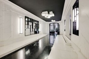 A modern hallway with white marble walls, black flooring, and contemporary lighting fixtures. - Superb apartment with terrace 2BR/4P Trocadero (Paris)