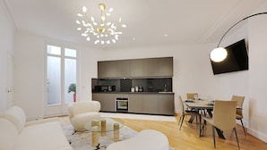 A modern living room with a sofa, a glass coffee table, and a dining area with chairs and a table. - Superb apartment with terrace 2BR/4P Trocadero (Paris)