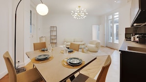A modern dining area with a table set for four, a sofa in the background, and a kitchen area to the right. - Superb apartment with terrace 2BR/4P Trocadero (Paris)