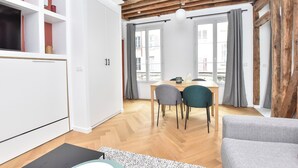 Un ambiente moderno con soffitto in legno, mobili bianchi, un'area pranzo con sedie e un divano.