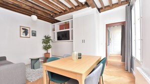 Un soggiorno moderno con soffitto in legno, un tavolo da pranzo con sedie, un divano grigio e un piccolo tavolino.