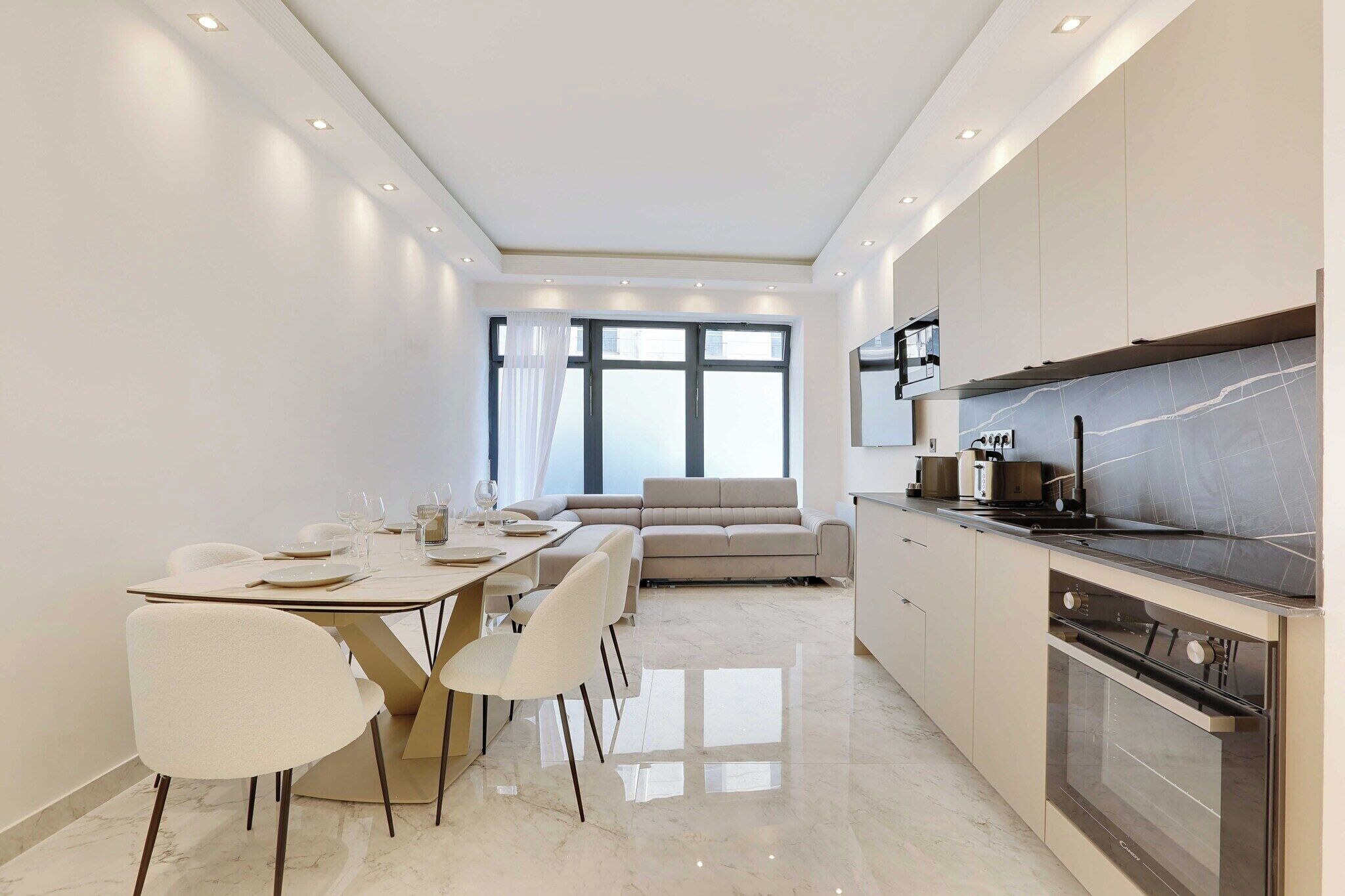 A modern kitchen with a dining area, large windows, and a built-in oven.