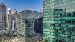 Een modern hoog gebouw met een spiegelende glazen gevel, omringd door andere hoge gebouwen.