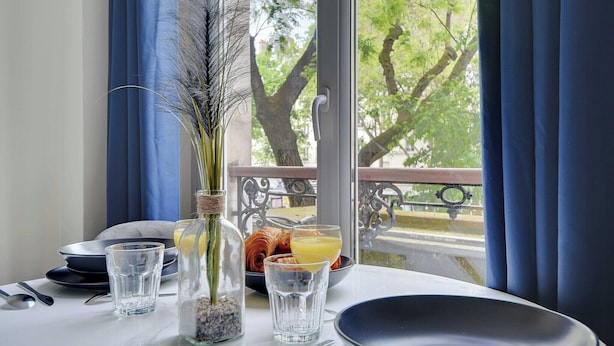 A breakfast table with plates, glasses, and a bottle of water. - Peaceful Studio -2P- Gare de l'Est/République (Paris)