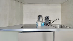 A modern kitchen with a stainless steel countertop, a coffee maker, a kettle, and a sink. - Peaceful Studio -2P- Gare de l'Est/République (Paris)