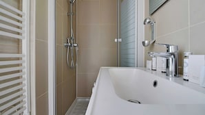 A modern bathroom with a white sink, a glass shower enclosure, and a mirror above the sink. - Peaceful Studio -2P- Gare de l'Est/République (Paris)