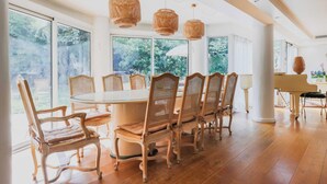 A spacious dining area with a round table and six wicker chairs, large windows with a view of greenery, and a grand piano in the background. - Exceptional apt with garden - 3BR/6P - Vincennes (Vincennes)
