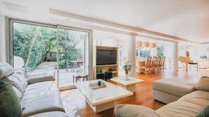A modern living room with a large TV, comfortable seating, and a view of a garden through large sliding doors. - Exceptional apt with garden - 3BR/6P - Vincennes (Vincennes)