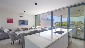 A modern kitchen with a large island, dining area, and a view of the outdoors. - Protaras Aqua Pearl Villa Aq11 (Paralimni)