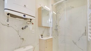 Een moderne badkamer met toilet, wastafel en douchecabine met glazen wanden.