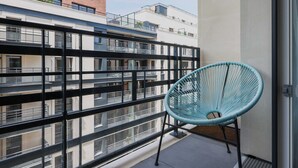 A balcony with a metal railing, a blue chair, and a view of neighboring buildings. - Classy appartement - Flea Market (Saint-Ouen-sur-Seine)