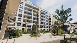 A multi-story residential building with balconies, a landscaped courtyard, and a sign indicating a space for sale. - Classy appartement - Flea Market (Saint-Ouen-sur-Seine)