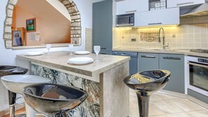 A modern kitchen with a stone archway, a central island with bar stools, a microwave, and a sink with a faucet. - Vacation home Bonita by Interhome (Medulin/Šišan)