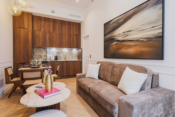 Una sala de estar moderna con un sofá marrón, una mesa redonda y un comedor con un aparador de madera y un cuadro en la pared.