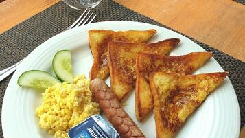 Enjoy a hearty breakfast on our table with a warm plate, fresh eggs, sausage, and a side of cucumber.