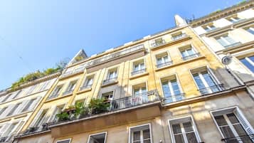 Un immeuble à plusieurs étages, doté de balcons, de grandes fenêtres et surplombant un ciel dégagé.