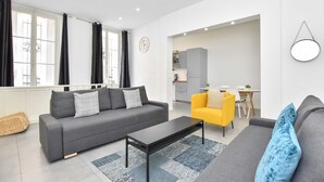 Un salon moderne avec un canapé gris, un fauteuil jaune et une table basse noire.