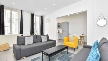 Un salon moderne avec un canapé gris, un fauteuil jaune et une table basse noire.