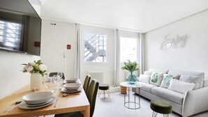 A modern living room with a dining area, a grey sofa, and a wall with the word "Enjoy". - Charming apartment - 1BR/4P - Faubourg-du-Roule (Paris)