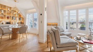 Een moderne woonkamer met een eethoek, grote ramen en uitzicht op de stad.