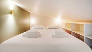 Ein modernes Hotelzimmer mit einem großen Bett, zwei Nachttischen und einer eingebauten Schrankwand.
