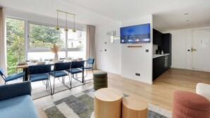Un saló modern amb zona de menjador, cuina i televisió penjada a la paret.