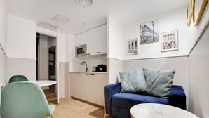 Un espace de vie compact comprenant un coin cuisine, un coin repas et un espace détente avec un canapé et une petite table.