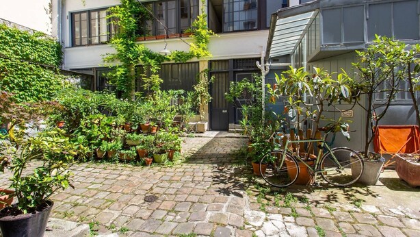 A courtyard with potted plants, a bicycle, and a building with a staircase. - Intimate apartment - 1BR/4P - Oberkampf (Paris)