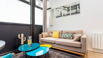 Un salon moderne avec un canapé, une petite table et une fenêtre.