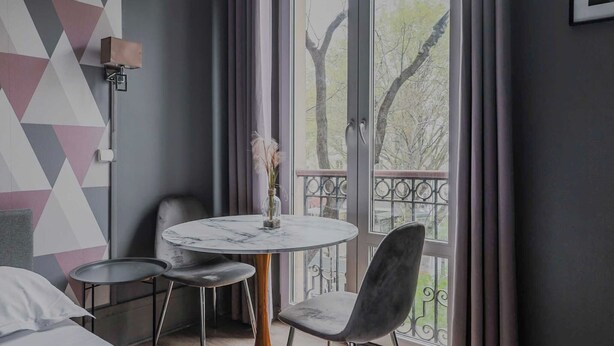 Una habitación moderna con una mesa redonda, dos sillas, una cama y un balcón con vistas.