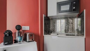 Una kitchenette compacta con microondas, tostadora y cafetera sobre una encimera blanca.