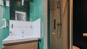 Un baño moderno con cabina de ducha de vidrio, un lavabo blanco y un espejo.
