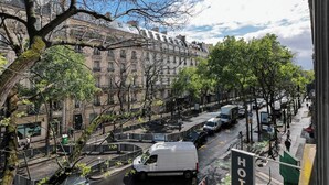 Vista de una calle con un edificio de arquitectura clásica, una camioneta blanca en la carretera y un cartel de hotel.