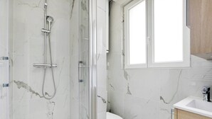 Un baño con ducha de vidrio, inodoro y lavabo con gabinete.