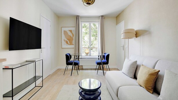 Una sala de estar moderna con un sofá, una mesa de centro, un televisor, una mesa de comedor con sillas y una ventana con cortinas.