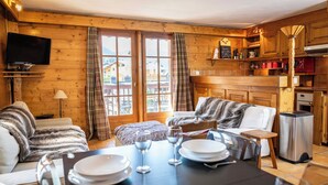 Un accogliente chalet in legno con zona pranzo, divano e televisione.