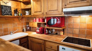 Una cucina con mobili in legno, un forno a microonde rosso, un tostapane e un lavello.