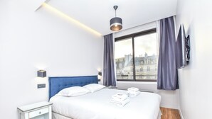 Ein modernes Hotelzimmer mit einem großen Bett, einem Nachttisch, einem Fenster mit Vorhängen und Blick auf die Stadt.