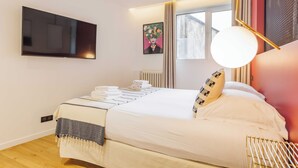Une chambre d’hôtel moderne dotée d’un grand lit, d’un téléviseur à écran plat fixé au mur, d’une fenêtre avec des rideaux et d’un luminaire au plafond au design original.