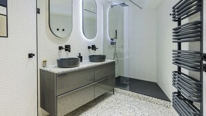Une salle de bain moderne avec deux lavabos, un grand miroir et une douche à parois de verre.
