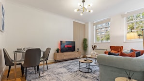Una sala de estar moderna con televisor, sofá y comedor.