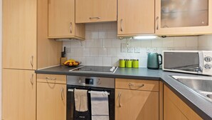 Una cocina con armarios de madera, un microondas, un hervidor y un cuenco de fruta en la encimera.