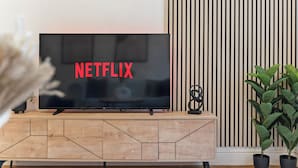 Un televisor de pantalla plana sobre un mueble de madera con la palabra "NETFLIX" mostrada en la pantalla.