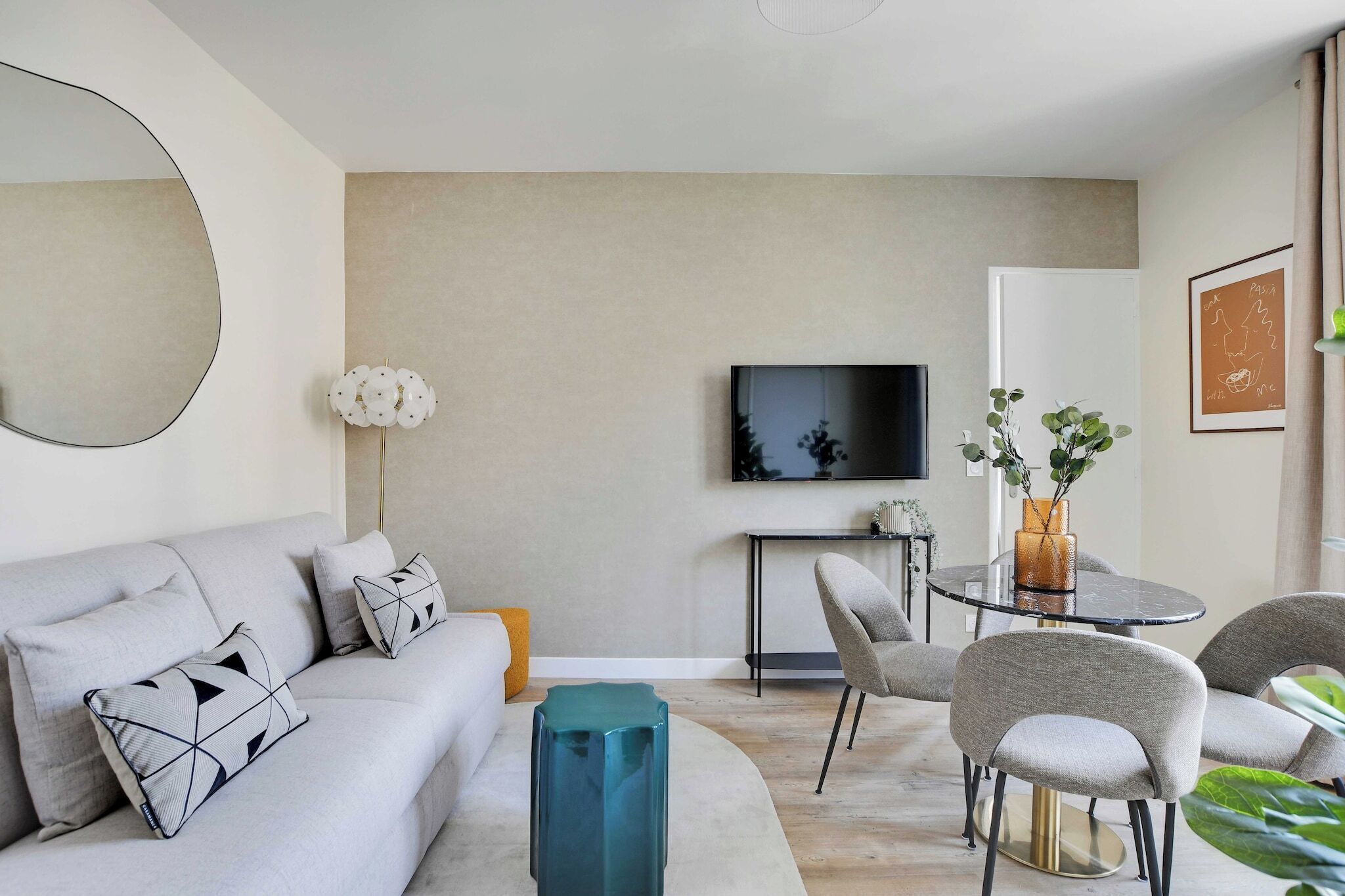 A modern living room with a sofa, chairs, a coffee table, a TV, and a small side table with a plant.