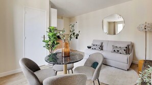 A modern living room with a round table, grey sofa, and a large mirror on the wall. - Cosy apartment - 1BDR-4P - Ivry-sur-Seine (Ivry-sur-Seine)