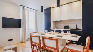 A modern kitchen with a dining area, a flat-screen TV, and a large window.