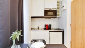 Een kleine keuken met een fornuis, magnetron en koffiezetapparaat op het aanrecht.